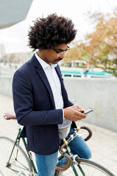 Spain, Barcelona, businessman on bicycle using cell phone in the city