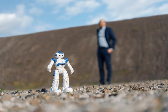 Miniature robot and businessman on a disused mine tip