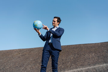 Mature businessman holding a globe on a disused mine tip