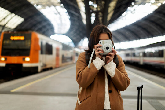 Young woman taking picture with camera at the train station