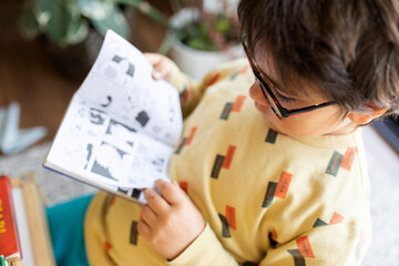 Little boy with glasses reading comic