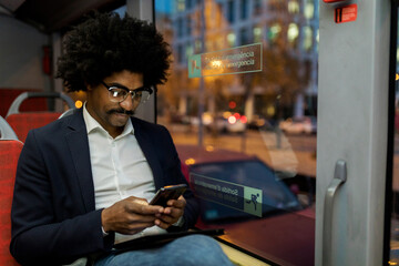 Spain, Barcelona, businessman in a tram at night using cell phone