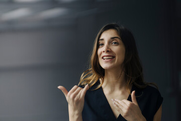 Portrait of gesturing young businesswoman against grey background