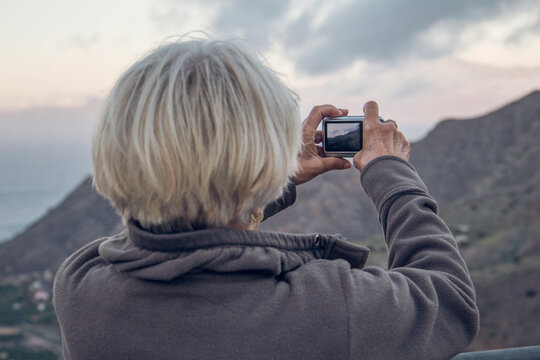 Spain, La Gomera, Hermigua, Senior woman taking picture with her digitsl camera, La Gomera, Spain