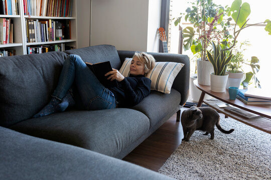 Mature woman relaxing on couch at home reading a book