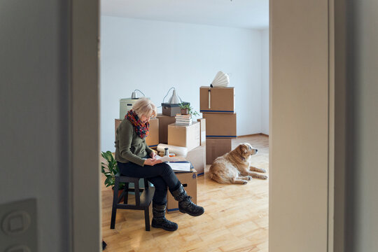 Senior woman looking at papers surrounded by cardboard boxes in an empty room