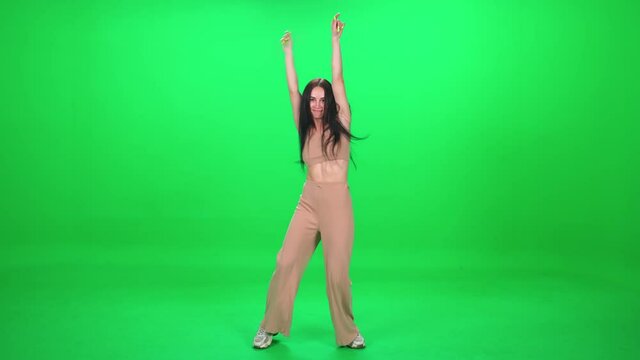 Caucasian cheerful female dancing vigorously at a music concert, dance and swing their arms on a green background, chromakey template.