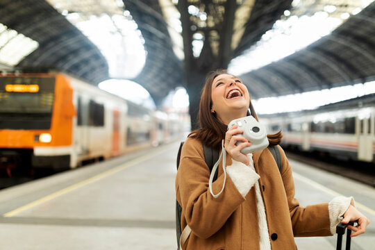 Happy young woman with camera at the train station