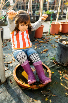 Little girl wearing Wellington Boots playing at pant nursery