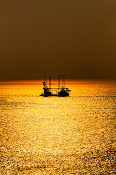 Offshore wind farm installation vessel sailing off in sea during sunset, West Coast, Scotland, UK