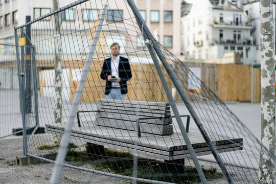Businessman behind ramshackle hoarding