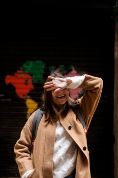 Happy young woman covering her face with her hand