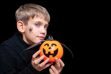 A child holding an orange pumpkin-shaped basket with a grinning face, Jack's lantern and a bat.