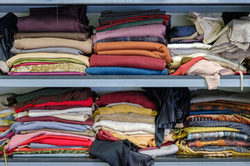 Multicolored various clothes stacked in piles on a shelf in a atelier