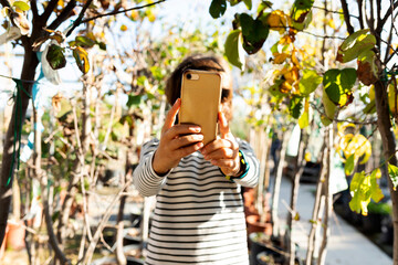 Hands of boy holden golden smartphone outdoors