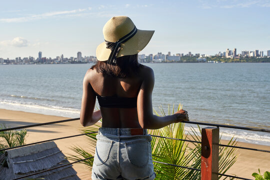Young woman at the waterfront looking at the skyline of Maputo, Mozambique