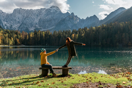 Couple holding hand on a bench at Laghi di Fusine, Friuli Venezia Giulia, Italy