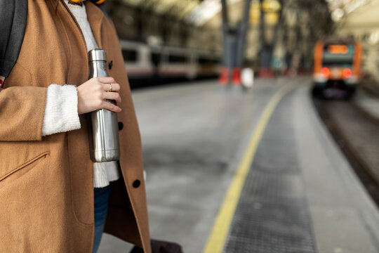 Close-up of woman holding thermos flask at the train station