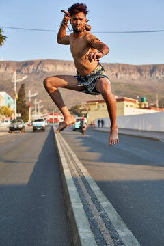 Tribal man with his traditional arch and arrows jumping on a median stripe, Lubango, Angola