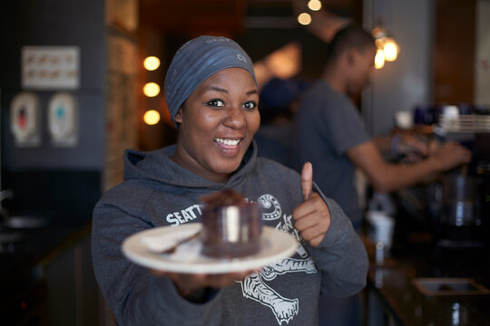 Young woman working at a coffee shop showing a cake