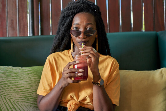 Young woman with dreadlocks drinking a smoothie in a cafe