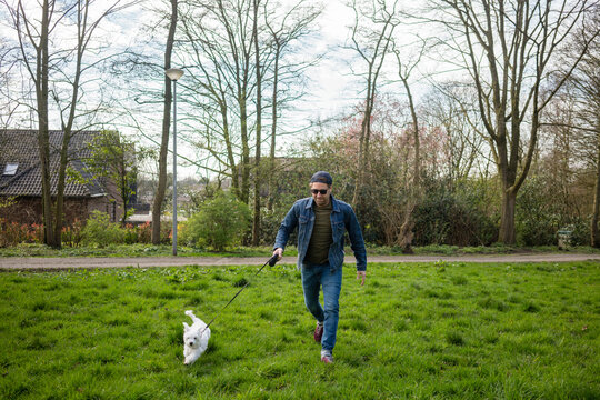 Smiling man running with dog on grass in yard