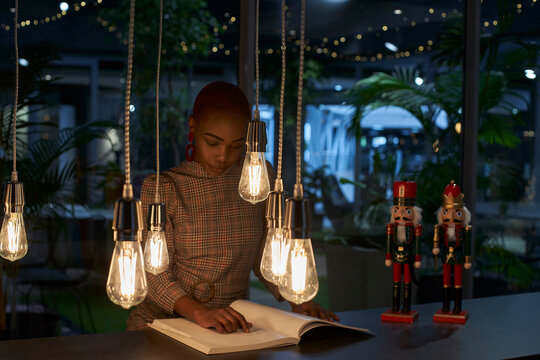 Young woman reading a book next to the nutcrackers on the table