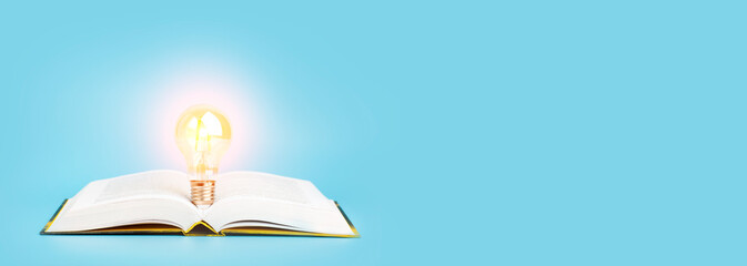 Knowledge study learning concept. Open book with a glowing light bulb on a blue banner background....