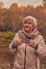 Portrait of a woman 65 years old against the background of autumn trees.