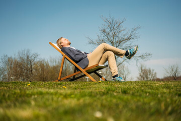 Surface level view of businessman relaxing on chair at park during sunny day