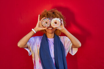 Playful woman holding two donuts in front of her eyes