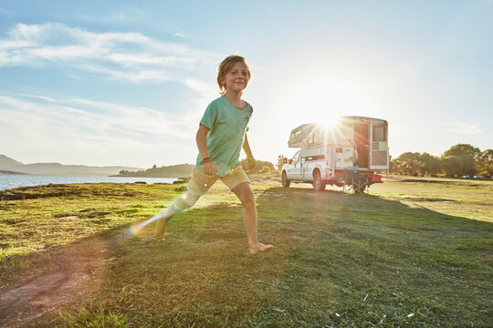 Chile, Talca, Rio Maule, boy running on meadowbeside camper at lake