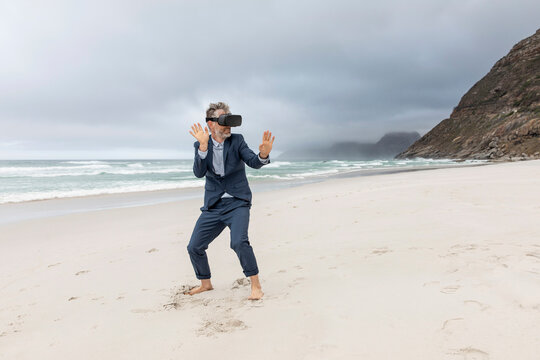 Businessman using VR glasses on the beach, Nordhoek, Western Cape, South Africa