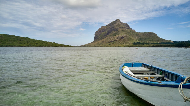 Mauritius, Empty rowboat floating in water with Le Morne Brabant peninsula in background