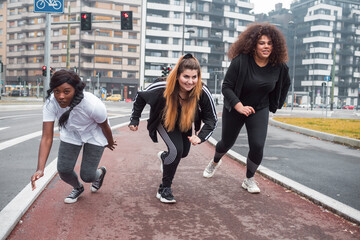 Three sportive young women training in the city
