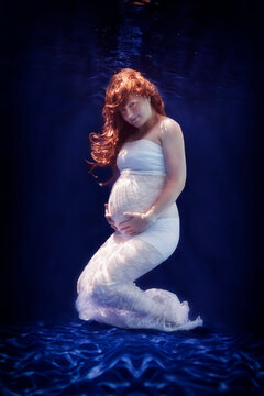 Pregnant woman wearing white dress under water