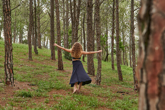 Back view of barefoot young woman dancing in the woods
