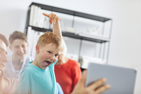 Little boy watching digital tablet with his family