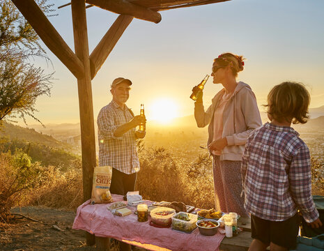 Chile, Santiago, mother with grandfather and son having a picnic in the mountains at sunset