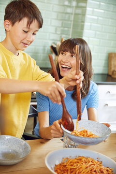 Mother eating spaghetti with her son in the kitchen