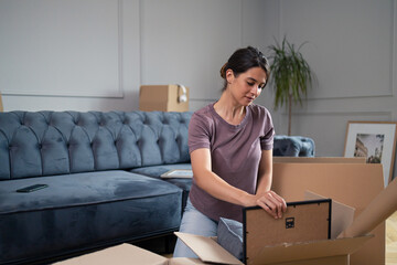 Young woman looking at picture frame after moving into ne apartment.