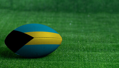 American football ball  with Bahamas flag on green grass background, close up
