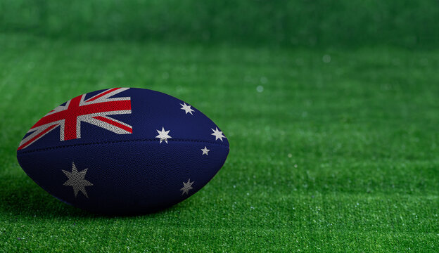 American football ball  with Australia flag on green grass background, close up - Powered by Adobe