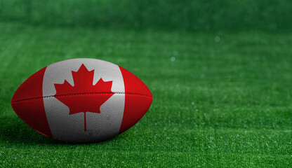 American football ball  with Canada flag on green grass background, close up