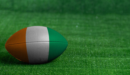 American football ball  with Code D Ivoire flag on green grass background, close up