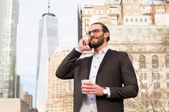 Smiling young businessman with coffee to go on the phone, New York City, USA