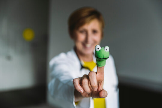 Close-up of happy doctor showing finger doll