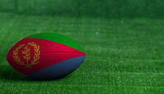 American football ball  with Eritrea flag on green grass background, close up