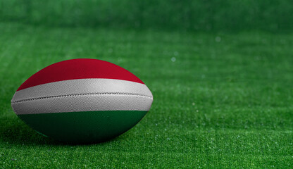 American football ball  with Hungary flag on green grass background, close up
