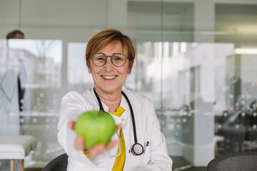 Portrait of smiling doctor holding an apple